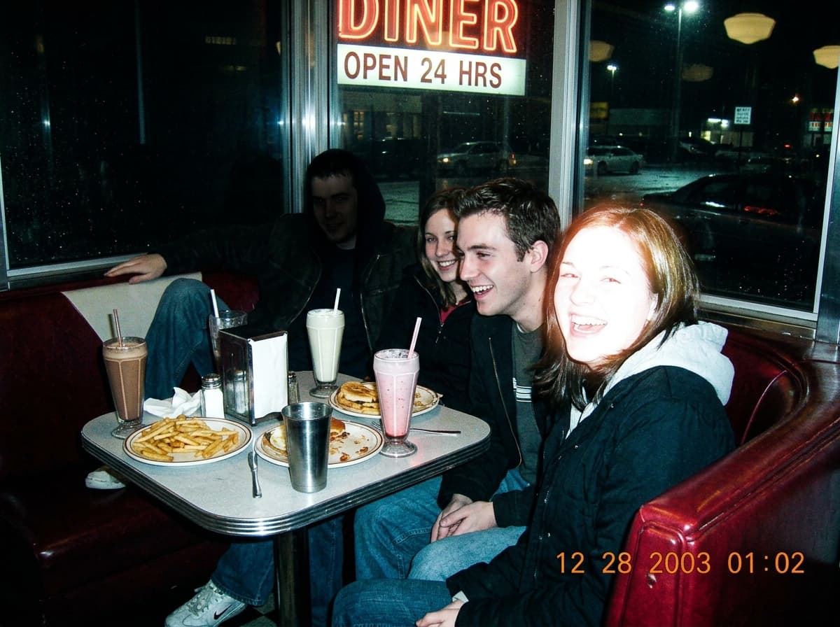 Y2K diner-booth photo with harsh pop-up flash and neon background