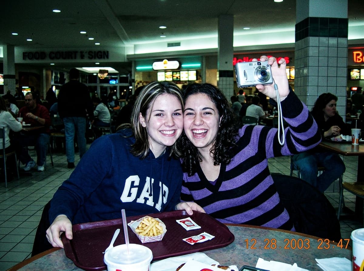 Y2K mall mirror selfie with compact digital camera and bright flash